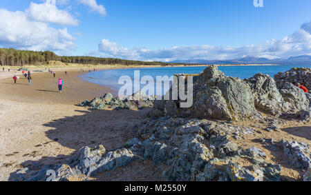 La passeggiata lungo la spiaggia di Llanddwyn verso l'isola, a Newborough su Anglesey. Snowdonia montagne sono in background. Foto Stock