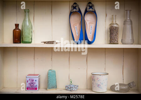La crema ripiani colorati con bottiglie vintage e scarpe da donna, dettaglio Foto Stock