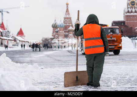 Meteo russa di Mosca. Lunedì, 5 febbraio 2018. La città si ravviva dopo la norma mensile di neve ha ottenuto lo scorso weekend. Servizi municipali di mobilitare tutte le loro risorse per pulire le strade e le piazze dallo spessore del tappeto bianco di fiocchi di neve. La temperatura è bassa, -10C (14F), ancora la luce della neve. Unidentified, irriconoscibile lavoratrice con un di legno shove in mani dal cumulo di neve sulla Piazza Rossa. Credito: Alex Immagini/Alamy Live News Foto Stock