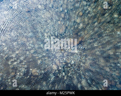 Vista aerea dell'acqua trasparente di un lago di montagna, ciottoli e pietre sul letto del fiume Foto Stock