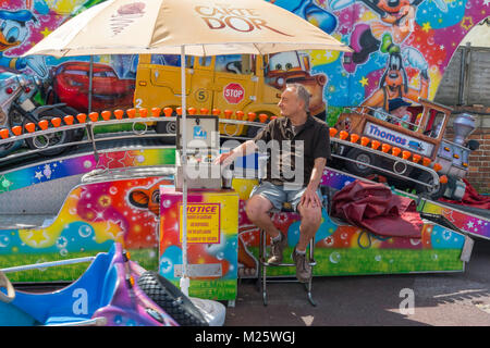 Lavoratore stagionale manning children's ride presso il parco di divertimenti in Dymchurch, Kent, Regno Unito. Foto Stock