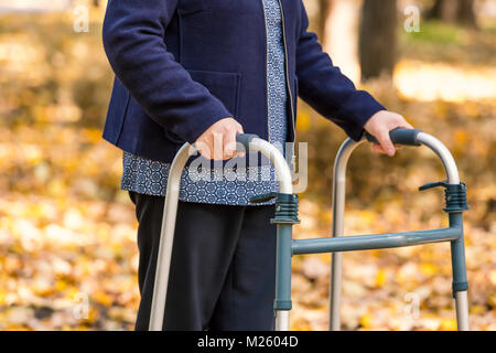 Primo piano della donna senior gambe camminando con walker in autunno park. Foto Stock