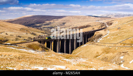 Carlisle, Inghilterra - Aprile 1, 2013: una classe 66 locomotiva diesel traina un treno merci attraverso Arten Gill viadotto, in alto sulle colline sopra Dentdale in E Foto Stock