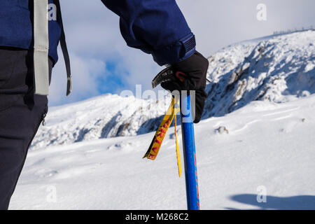 Escursionista tenendo una piccozza in mano le escursioni su Rhyd Ddu percorso in corrispondenza Llechog con Snowdon in inverno la neve. Parco Nazionale di Snowdonia (Eryri) Wales UK Gran Bretagna Foto Stock