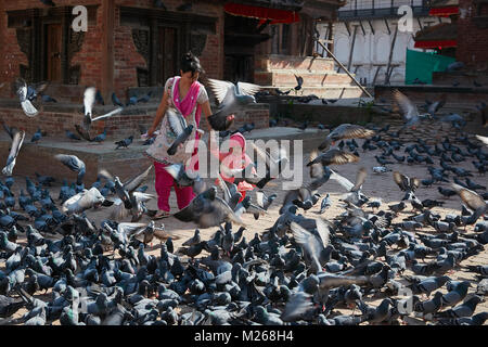 La madre e il bambino ragazza camminare a Durbar Square, Kathmandu, Nepal circondato da battenti street piccioni Foto Stock