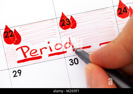 Dita di donna con penna scrittura periodo promemoria nel calendario. Close-up. Foto Stock