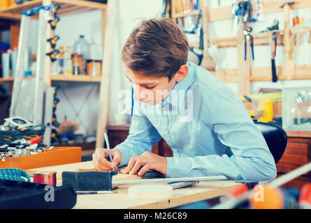 Allegro adolescente europea sorridente e la lavorazione del legno in officina Foto Stock