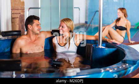 L uomo e la donna sono godendo di rilassarsi e di parlare in piscina in spa salone Foto Stock