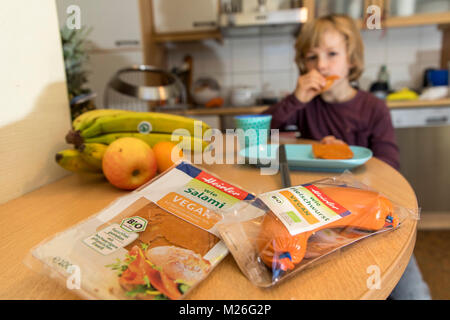 Il ragazzo, 7 anni, la degustazione di cibi vegan, salsiccia prodotti sostitutivi, salame vegan, vegan la salsiccia di carne, Foto Stock