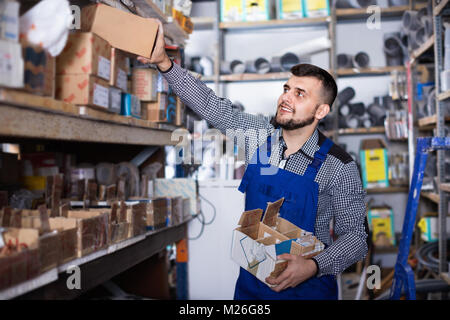 Allegro uomo lavoratore andando attraverso ingegneria sanitaria dettagli in officina Foto Stock