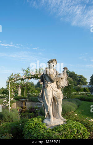 Una statua di pietra di un liuto giocatore nel parterre di rose nel giardino murato a Houghton Hall, King's Lynn, Norfolk, Regno Unito Foto Stock