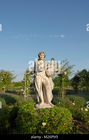 Una antica statua di pietra di un musicista nel parterre di rose a Houghton Hall, King's Lynn, Norfolk, Regno Unito Foto Stock