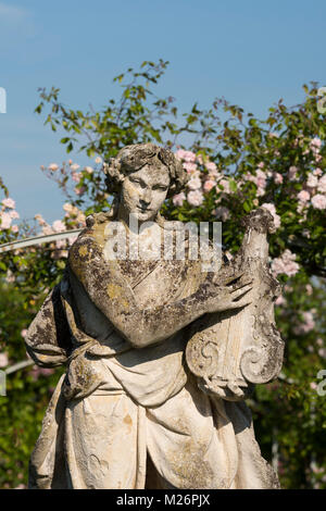 Un close-up di un antica statua di pietra nel parterre di rose a Houghton Hall, King's Lynn, Norfolk, Regno Unito Foto Stock