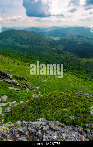 Montagna dietro la valle vista dalla scogliera rocciosa. bellissimo paesaggio estivo con pendii erbosi sotto il cielo nuvoloso. Ubicazione Pikui montagna, Trans Foto Stock