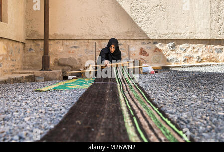 Nizwa, Oman, febbraio 2nd, 2018: omani weawing donna un tappeto Foto Stock