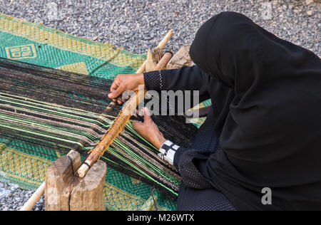 Nizwa, Oman, febbraio 2nd, 2018: omani weawing donna un tappeto Foto Stock