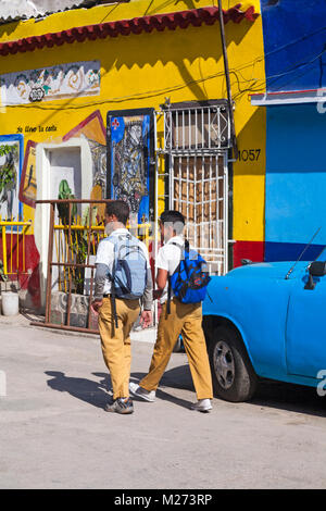 Due ragazzi della scuola a piedi passato illustrazione cubano di Jack of Clubs carta da gioco dipinto sul muro a Callejon de Hamel, Havana, Cuba, West Indies Caraibi Foto Stock
