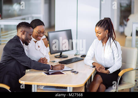 African giovane getting chiave auto dal concessionario in showroom e firma contratto Foto Stock