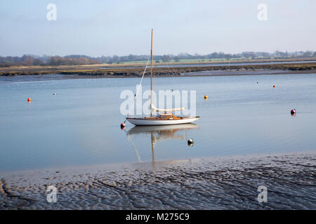 Uno yacht ormeggiati off shore fangoso calme acque del fiume, Deben Waldringfield, Suffolk, Inghilterra, Regno Unito Foto Stock