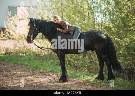 Pilota giovane ragazza con i capelli lunghi che giace sul collo del cavallo Foto Stock