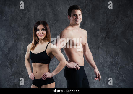 Fitness sana sportività giovane uomo e donna su uno sfondo scuro Foto Stock