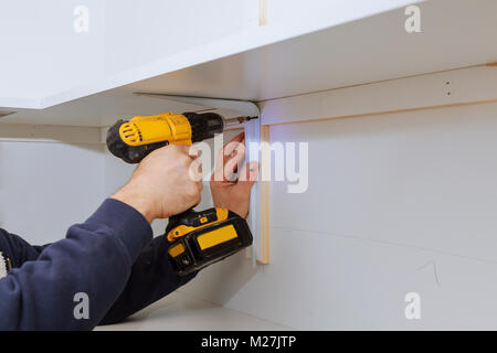 L'uomo installazione di scaffalature in legno su staffe installazione di ripiani Foto Stock