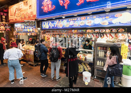 Hong Kong - 25 Gennaio 2018: la gente acquista vari street food snack, come ad esempio la carne e il pesce palle su spiedini, in una fase di stallo in strade affollate di Mong Foto Stock