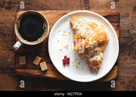 Croissant e la tazza di caffè espresso sul vecchio tavolo in legno. Vista dall'alto. Concetto di colazione Foto Stock