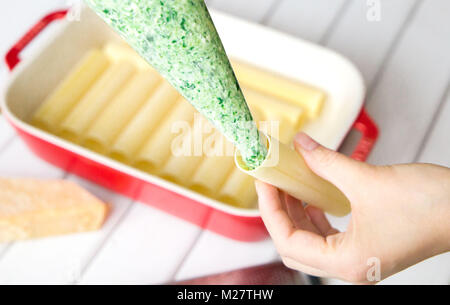 Primo piano di spinaci e formaggio cannelloni preparazione : ripieno i cannelloni con gli spinaci e ripieno di formaggio Foto Stock