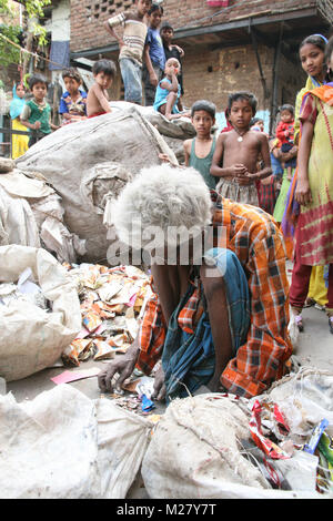 Un vecchio uomo passa attraverso la spazzatura per le strade di una baraccopoli di Delhi, India, Asia Foto Stock