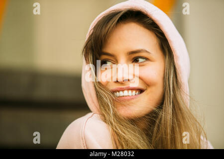 Cool Parigamba giovane donna in rosa hoodie sorridente Foto Stock