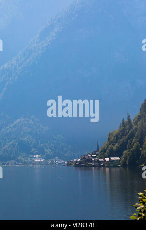 Vista del paesaggio di montagna in legno case lungo lago tra Austrian Alp montagne del Salzkammergut sul cielo blu sullo sfondo. Foto Stock