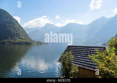 Vista del paesaggio di montagna in legno case lungo lago tra Austrian Alp montagne del Salzkammergut sul cielo blu sullo sfondo. Foto Stock