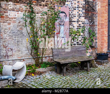 Berlino, Prenzlauerberg, cortile interno della ex fabbrica di birra Königstadt. Area salotto all'aperto con panca & arte sul vecchio muro in mattoni. Foto Stock