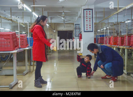 (180206) -- SHISHI, 6 febbraio 2018 (Xinhua) -- Huang Hailong, insieme con la moglie e il figlio più giovane si sono visti nella fabbrica di abbigliamento in Shishi City, a sud-est della Cina di provincia del Fujian, Gennaio 31, 2018. Huang Hailong, un lavoratore migrante da Suining città del sud-ovest della Cina di provincia di Sichuan, ha lavorato in una fabbrica di abbigliamento in Shishi per dieci anni. Pur vivendo con la moglie e il figlio più giovane Cong Cong, Huang è ancora mancante i suoi genitori e il figlio maggiore che vivono nella zona montuosa del Sichuan. Quest'anno, al fine di risparmiare denaro, Huang ha deciso di tornare da solo alla sua città natale per trascorrere la molla Festiva Foto Stock