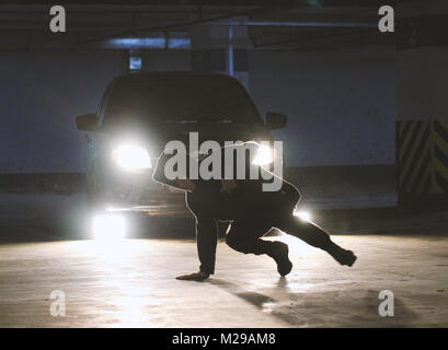 L'uomo freerunner lato facendo capriole in garage, parkour elementi acrobatico Foto Stock