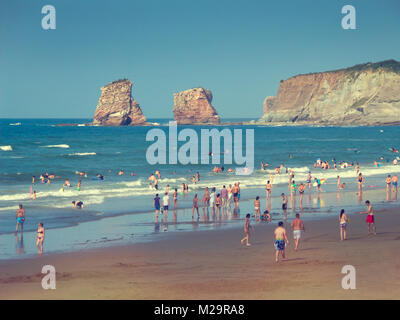 La gente sulla spiaggia di Hendaye in Francia, i Gemelli rocce dello sfondo Foto Stock