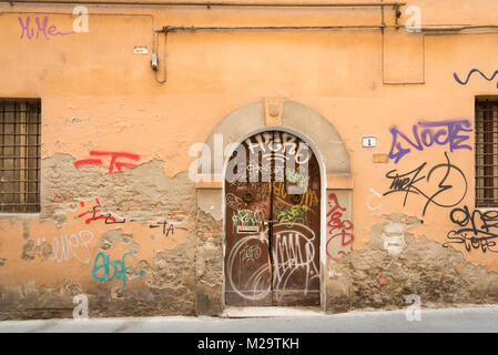 Graffiti spruzzato in vernice bianca su una vecchia porta di legno in Bologna Italia Foto Stock