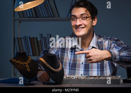 Giovane maschio gioielliere lavorando di notte nel suo laboratorio Foto Stock