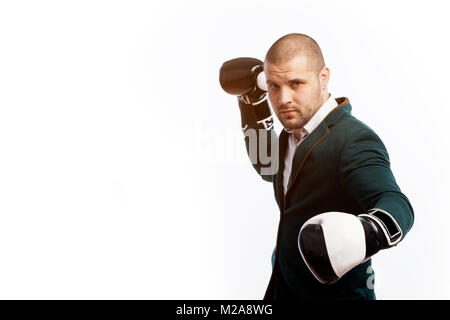 Giovane uomo calvo, fiducioso business man in maglia bianca, verde tuta e guantoni da pugilato facendo un uppercut, boxe bianco su sfondo isolato Foto Stock