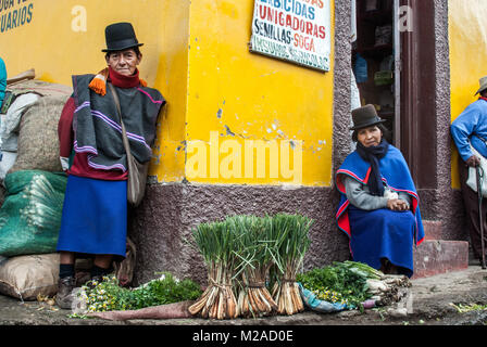 Un indigeno Guambiano giovane vendita di produrre nella parte anteriore di un colore giallo brillante parete a Silvia, Colombia Foto Stock