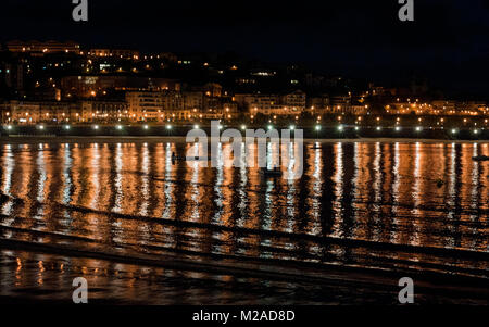 Riprese notturne di luci da edifici riflessa nella baia di San Sebastian, Spagna Foto Stock