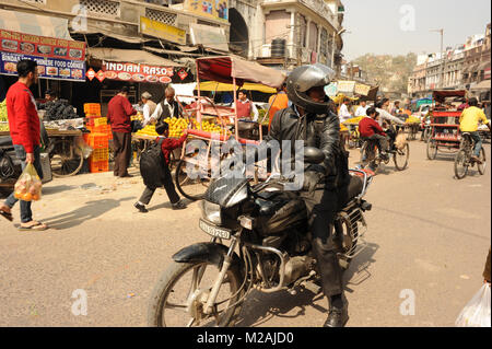 Un uomo che cavalca una moto su strada trafficata in Paharganj, India Foto Stock