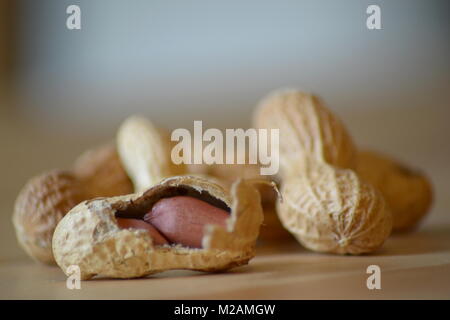 Qualsiasi chiuso e aperto arachidi giacciono su di un tavolo di legno. Foto Stock