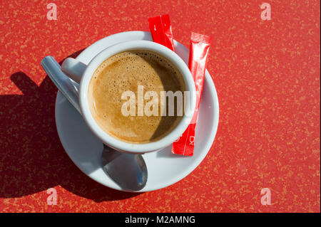Tazza di caffè fresco su una rossa cafe tabella visto dal di sopra. Foto Stock