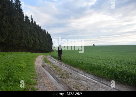 A lone man stands next to a green field Foto Stock
