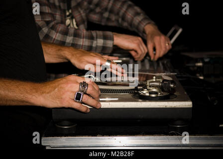 Close up DJ due mani la riproduzione di vinili sui loro deck di registrazione a una festa in una discoteca Foto Stock