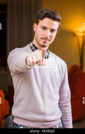 Bel giovane puntare il dito a voi, sorridente Foto Stock