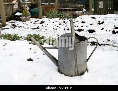 Un vecchio acciaio zincato annaffiatoio in piedi in una coperta di neve riparto giardino, North East England, Regno Unito Foto Stock