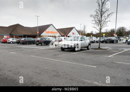 Sainsbury's parcheggio auto su un opaco mattino cielo coperto in inverno, Dorset, Regno Unito Foto Stock